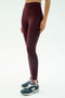 Model wears SPLITS59 Amber Airweight High Waist 7/8 leggings in Dark Cherry/Indigo, paired with black New Balance sneakers, against a plain white background.