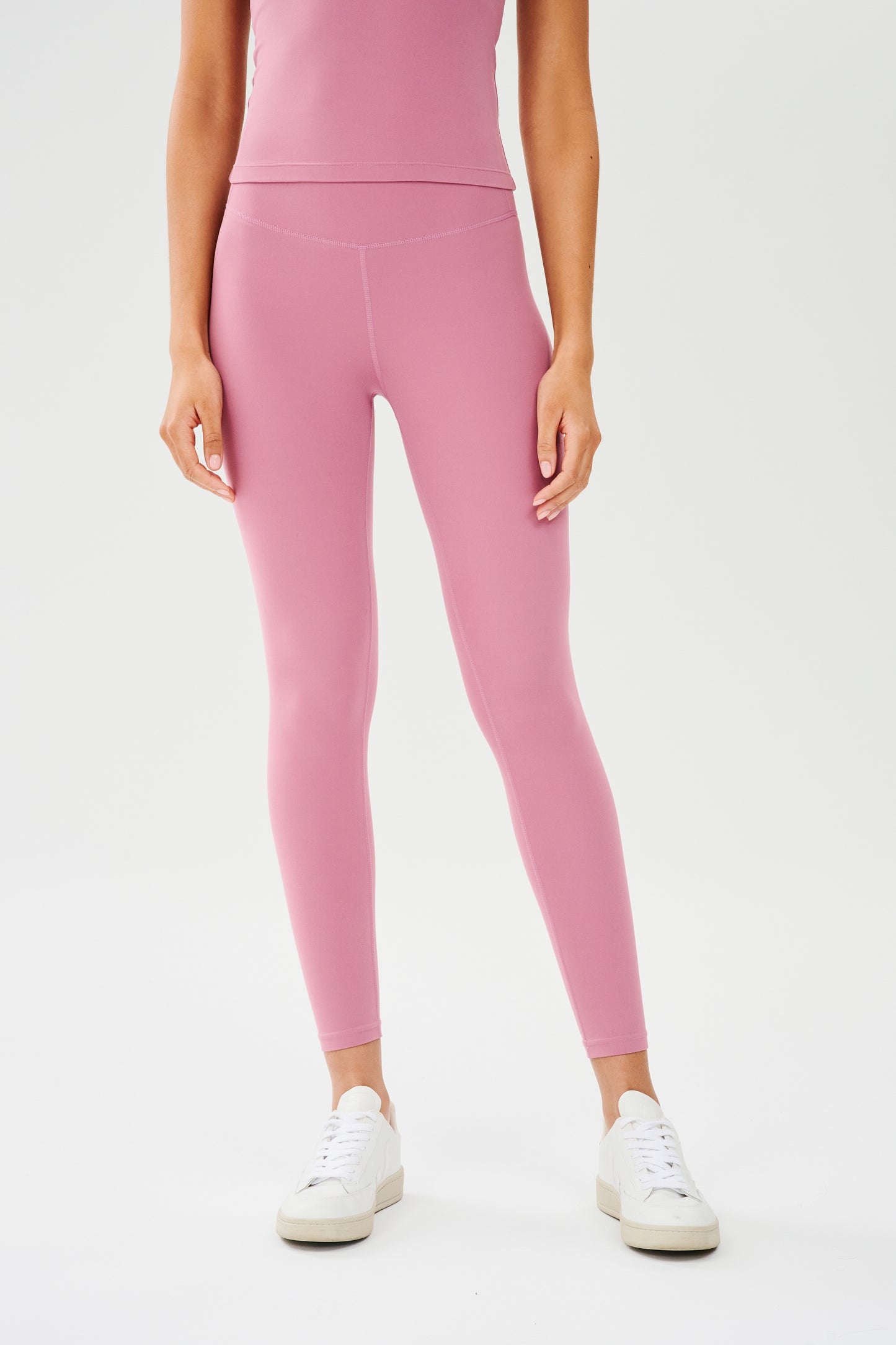 Front view of girl wearing highwasited pink leggings with white shoes