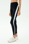 A person wears SPLITS59 Emerson Airweight High Waist leggings in Black/Ice, featuring white and light blue side stripes, paired with white sneakers—ideal for hot yoga or Pilates—posed against a plain background.
