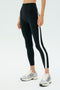 Wearing SPLITS59’s Miles High Waist Rigor 7/8 leggings in Black/White with side stripes and silver running shoes, this look is perfect for gym sessions or active days against a minimal background.
