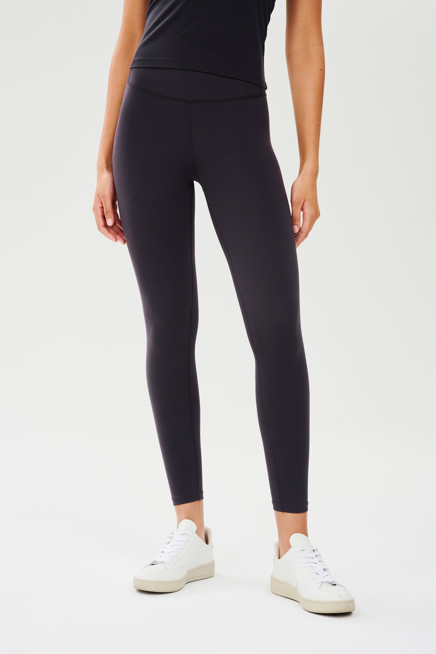 Front view of girl wearing highwasited black leggings with white shoes