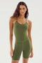 A person with long hair wears the SPLITS59 Airweight 6” Short Jumpsuit in Olive, a body-hugging, sleeveless design made from airweight fabric, standing against a plain white background.