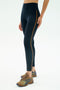 A person in SPLITS59 Amber Airweight High Waist 7/8 leggings in Indigo/Honey stands against a plain white background, paired with tan athletic shoes.