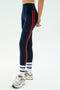 A person wearing SPLITS59 Ella High Waist Airweight 7/8 leggings in Indigo/Pirate Red, paired with white socks with blue text and gray sneakers, stands against a plain light background.