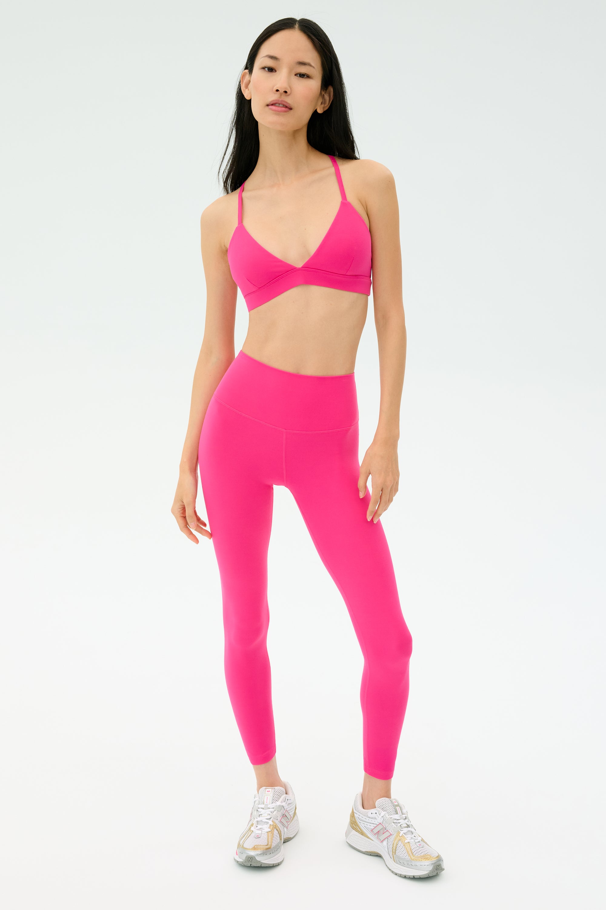 A person faces forward wearing the SPLITS59 Sprint High Waist Rigor 7/8 - Berry set with white athletic shoes against a plain light background.