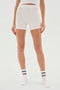 Person wearing white, mid-thigh Theo Rib Short - White from SPLITS59, a white top, and white socks with black stripes, standing against a plain white background. A perfect blend of tailored comfort and classic design.