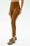 A person wearing SPLITS59 Amber Airweight High Waist 7/8 leggings in Honey/Indigo, paired with multicolored running shoes, stands against a plain background.