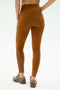 A person is shown from the back wearing SPLITS59 Amber Airweight High Waist 7/8 leggings in Honey and Indigo on a white background.