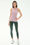 A woman faces forward against a white background, wearing the SPLITS59 Kiki Rib Tank Full Length in Blush, green spandex leggings with purple side stripes, and white sneakers.