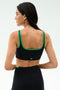 A woman is shown from the back in the SPLITS59 Cait Rigor Bra - Black/Grass, featuring green trim and high-performance Rigor fabric—ideal for high-impact workouts—against a plain light background.