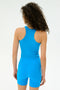 A person with curly hair is wearing the SPLITS59 Ashby Rib Crop - Riviera, standing with their back to the camera against a plain background.