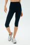 A person is wearing SPLITS59 Airweight High Waist 16" Legging in Indigo and white athletic shoes, standing against a plain light background.