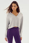 A person is wearing a Heather Grey Joan Fleece Polo Sweatshirt by SPLITS59 and high-waisted purple leggings made with a comfortable blend of spandex. They are posing against a plain background.
