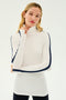 A woman with long blonde hair is wearing a SPLITS59 Jackson Rib Full Length Turtleneck in White/Indigo, featuring 2x1 baby rib neck to cuff sleeve stripes. She stands confidently against a plain white background.