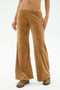 Someone wearing SPLITS59's Joy Velour Pant in Honey, featuring tan wide-leg design in polyester-spandex, and colorful sneakers, with a partially visible torso against a plain light background.
