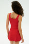 A person with curly hair is shown from behind, wearing the SPLITS59 Martina Rigor Dress in red against a plain light background.