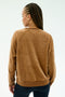 A person with braided hair is seen from the back, wearing the SPLITS59 Joy Velour Crewneck in Honey and dark pants, standing against a plain light background.