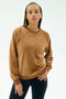 A person wearing the SPLITS59 Joy Velour Crewneck in Honey and black pants stands against a plain light background, looking towards the camera.