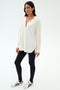 A woman stands against a white background wearing the SPLITS59 Kate Airweight Lite Button Down in white, paired with black leggings and white sneakers with black accents—an ideal lightweight layer for effortless style.