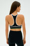 Individual sporting the SPLITS59 Layla Airweight Bra in black with arugula green accents, seen from behind.