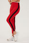Front side view of woman wearing bright red leggings with black side stripes and white waistband paired with white shoes