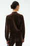A person with dark hair in a bun is shown from the back, warming up in the SPLITS59 Heritage Velour Bomber - Dark Chocolate/Classic Blue against a plain white background.
