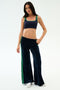 Model in SPLITS59 Heritage Velour Pant in Indigo/Grass, featuring soft navy velour with green stripes and a modern ankle-length wide leg, poses against a plain white background.