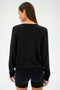 Individual wearing a stylish SPLITS59 Bennie Fleece V-Neck Sweatshirt in black and shorts, facing away.