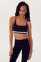 A person with long hair wearing a SPLITS59 Bianca Rigor Bra - Black with red trim and matching black leggings with red stripes, both made from a blend of nylon and spandex fabric, stands against a plain white background.