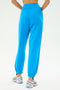 Model wearing SPLITS59's Andie Oversized Fleece Sweatpant in bright blue, paired with white athletic shoes, shown from the back against a plain light background.