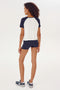 The back view of a woman wearing a navy and white SPLITS59 Airweight High Waist 3.5” Short - Indigo t-shirt.