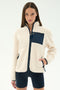 A woman models the SPLITS59 Harris Sherpa Jacket in Creme/Indigo, featuring navy zippers and front pockets, paired with black shorts against a plain white background.