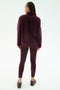 A person stands facing away against a white background, wearing SPLITS59's Harris Sherpa Jacket in Dark Cherry, paired with matching leggings and sneakers.