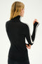 A person with blond hair is shown from the back, wearing a black Jackson Rib Full Length Turtleneck - Black/White by SPLITS59, featuring white stripes down the sleeves. The person is holding their right hand up near their neck.