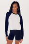 A woman in a Indigo/White Warm Up Crop Fleece Sweatshirt by SPLITS59, paired with black spandex shorts, standing against a white background.