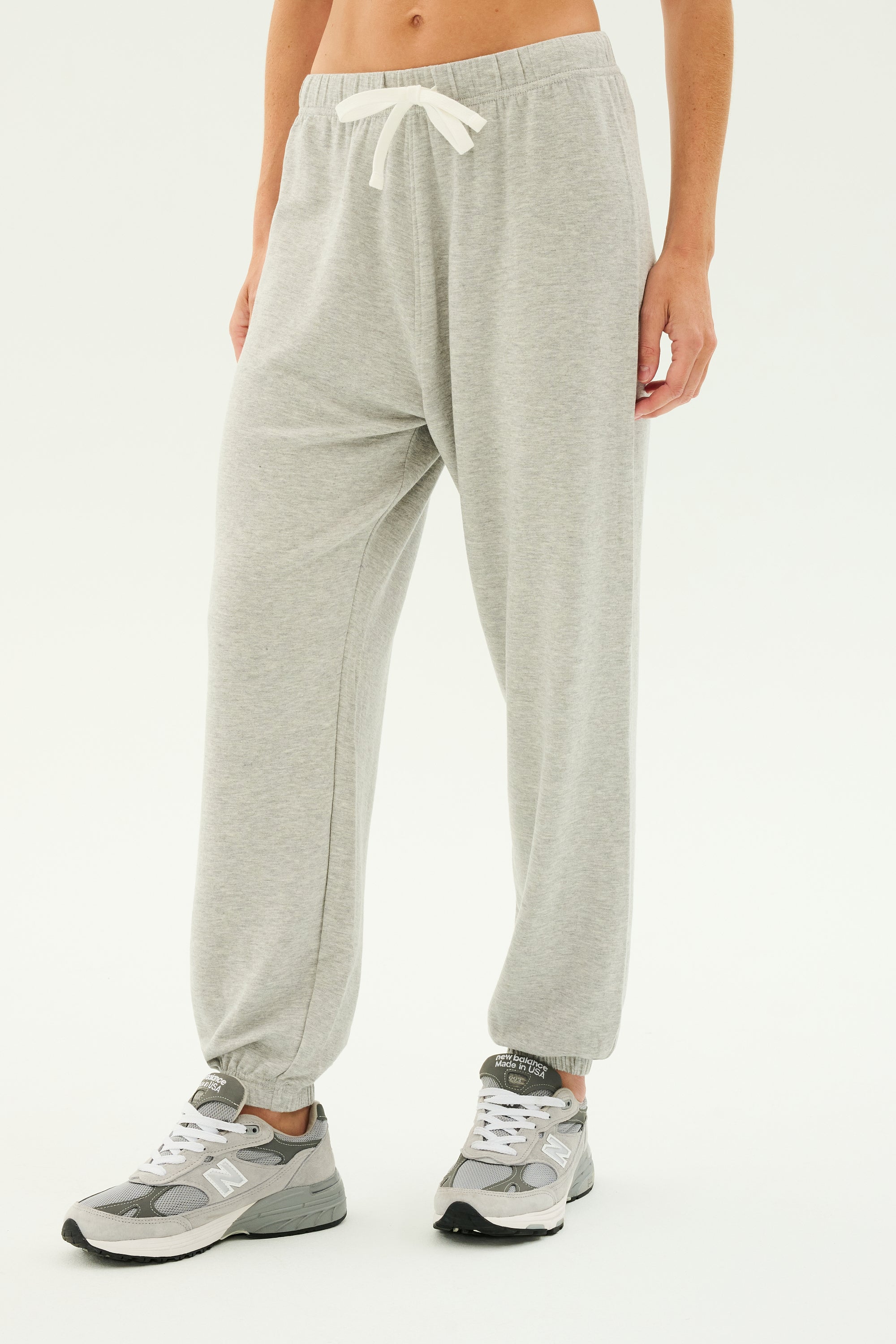 Person wearing SPLITS59 Andie Oversized Fleece Sweatpant in Heather Grey with a white drawstring and grey sneakers, ideal for cool weather workouts or warm-ups, standing against a plain background.