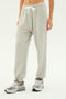 Person wearing SPLITS59 Andie Oversized Fleece Sweatpant in Heather Grey with a white drawstring and grey sneakers, ideal for cool weather workouts or warm-ups, standing against a plain background.