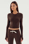 A person with long hair wears the SPLITS59 Louise Rib Long Sleeve Crop in Dark Chocolate and matching brown drawstring pants against a plain background.