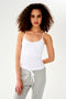 A woman in a Loren Seamless Waist Length Tank in White by SPLITS59 with a shelf bra and grey sweatpants.