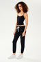 A woman wearing black sweat pants and a white, chafe-free fabric SPLITS59 Loren Seamless Waist Length Tank - Black.