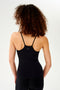 A woman with curly hair wearing a SPLITS59 Loren Seamless Waist Length Tank in Black.