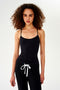 A woman wearing a SPLITS59 Loren Seamless Waist Length Tank in Black and black sweatpants.