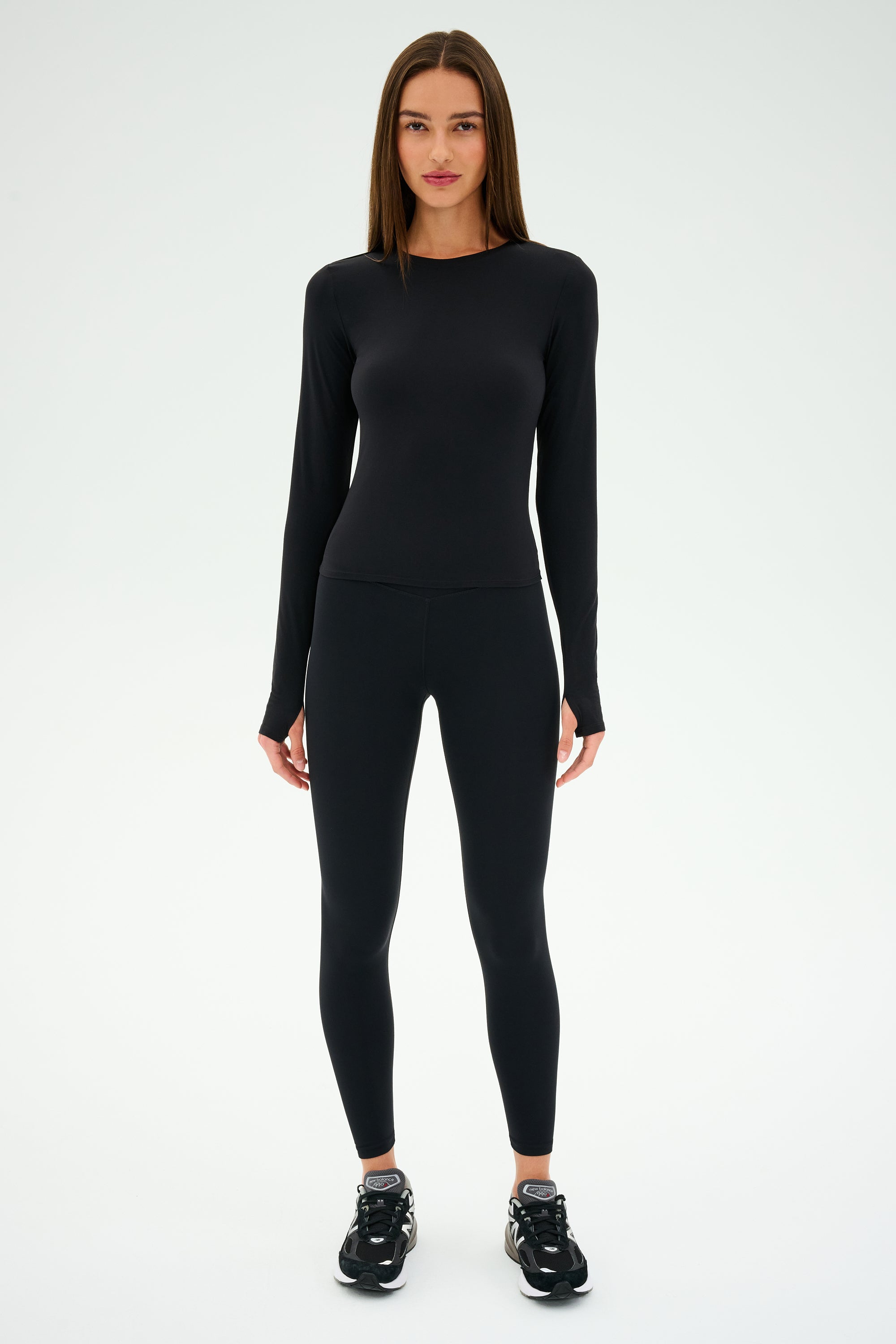 Wearing the SPLITS59 Airweight Lite LS Waist Length in black, paired with airweight leggings, this individual stands against a white background—ideal for intense workouts or everyday comfort.