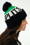 A person in profile wearing a green, white, and black beanie with a pom-pom and the word "SPLITS59" knitted on the hat.