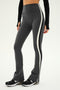 Person wearing SPLITS59 Raquel High Waist Flared Legging in Heather Grey with a white stripe along the side, paired with a black long-sleeve crop top and black-and-white sneakers.