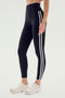 Wearing SPLITS59 Ella High Waist Airweight 7/8 leggings in Black/White with white side stripes and white sneakers, standing against a plain background—ideal for hot yoga or casual wear.