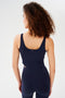 Back view of woman with curly dark brown hair wearing a dark blue bra crop tank with dark blue leggings