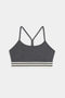 The Cali Active Rib Bra by SPLITS59 features a gray ribbed design, thin shoulder straps, a racerback, and a white-and-black striped elastic band at the bottom.