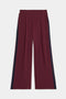 The SPLITS59 Luca Airweight Trouser with Stripe features a wide-leg maroon design, navy side stripes, an elastic waistband, and side pockets, shown laid flat on a white background.