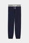 The Andie Oversized Fleece Sweatpant with Stripe by SPLITS59 features navy blue fabric, elasticated cuffs, a white drawstring, and a white waistband accented by two navy stripes.